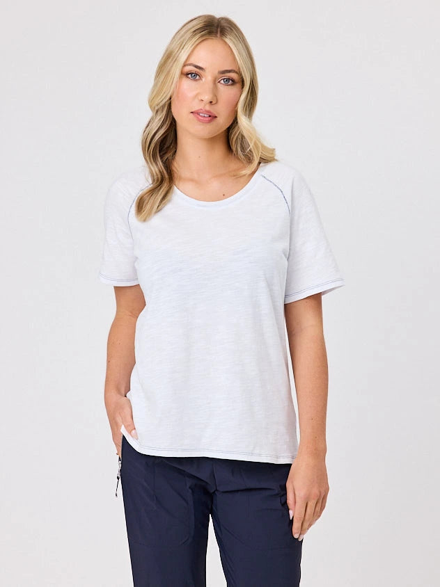 Woman wearing a white cotton t-shirt by Navy & Co, standing front-facing in natural light