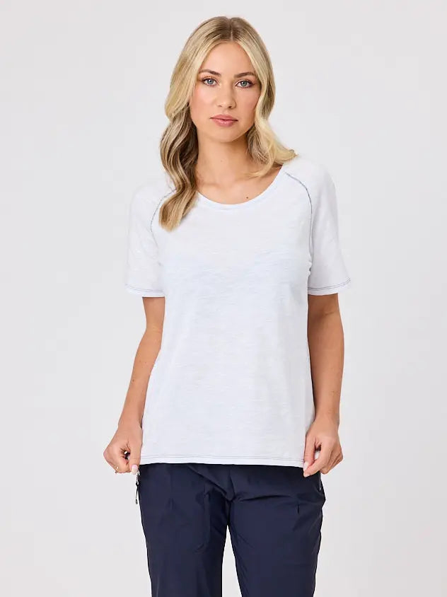Woman wearing a white cotton t-shirt by Navy & Co, standing front-facing in natural light