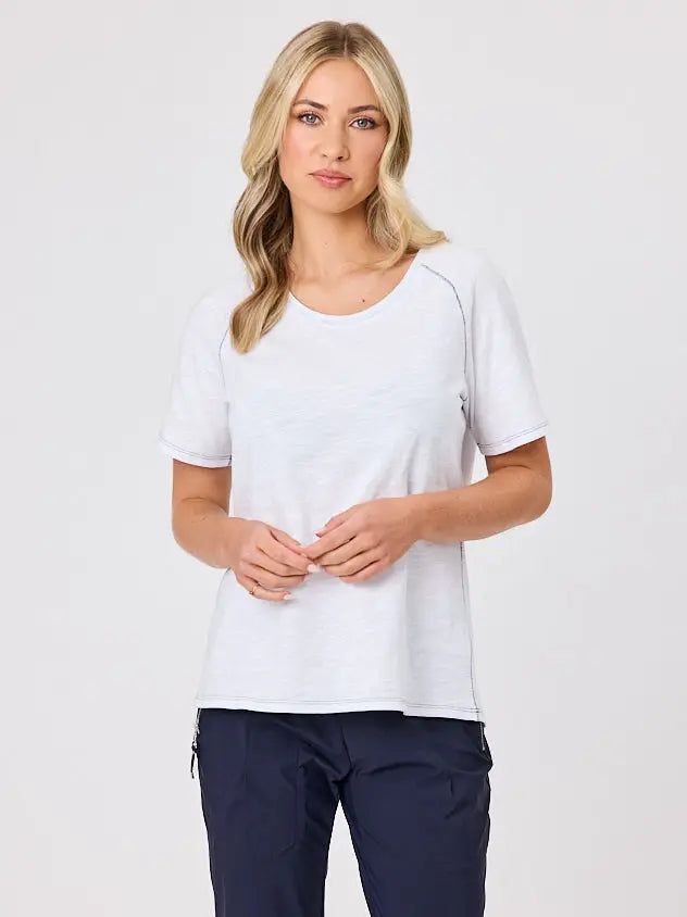 Woman wearing a white cotton t-shirt by Navy & Co, standing front-facing in natural light