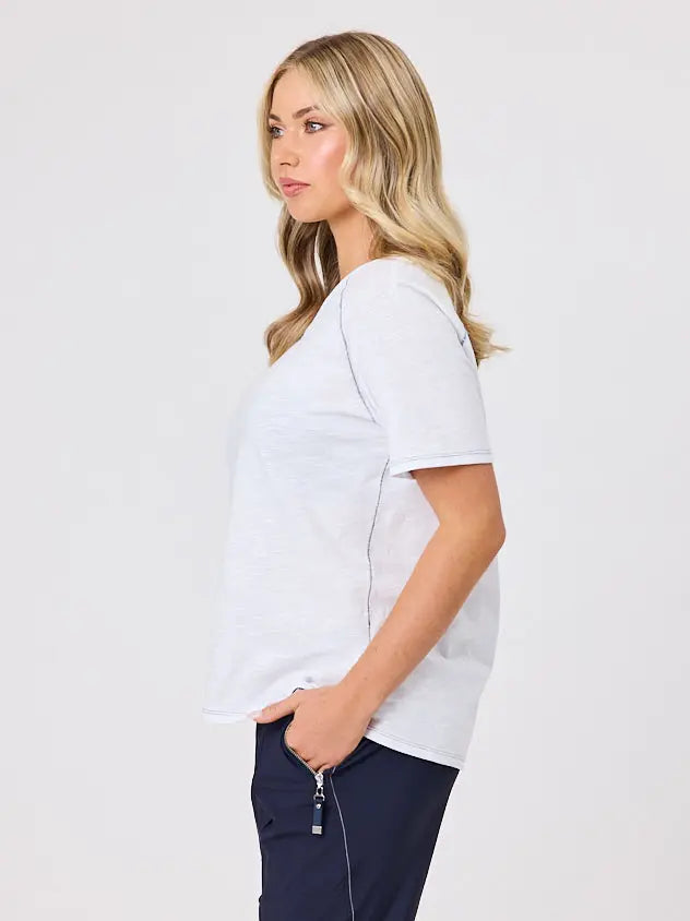 Woman wearing a white cotton t-shirt by Navy & Co, standing front-facing in natural light
