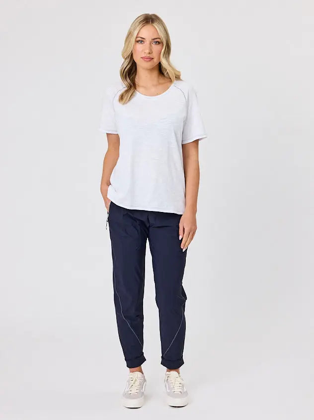 Woman wearing a white cotton t-shirt by Navy & Co, standing front-facing in natural light