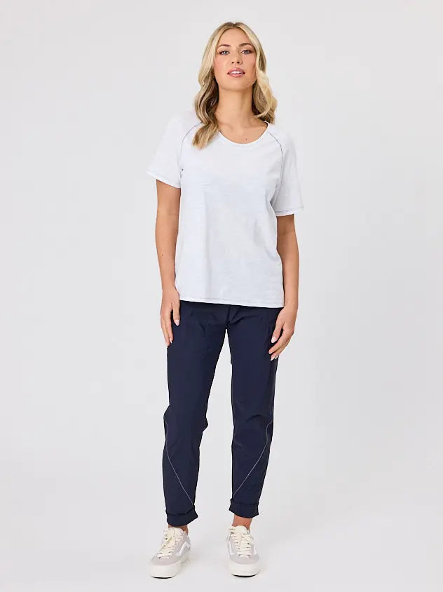 Woman wearing a white cotton t-shirt by Navy & Co, standing front-facing in natural light