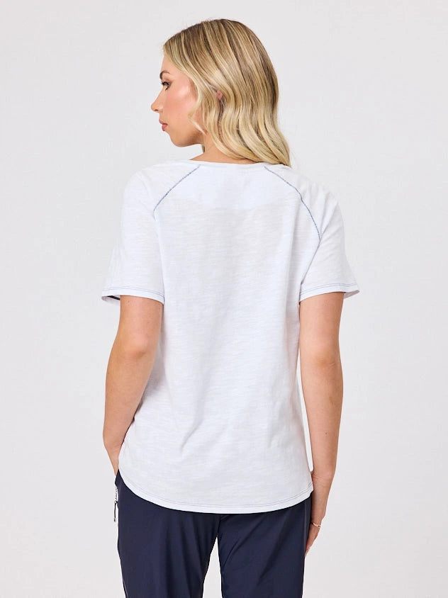 Woman wearing a white cotton t-shirt by Navy & Co, standing front-facing in natural light