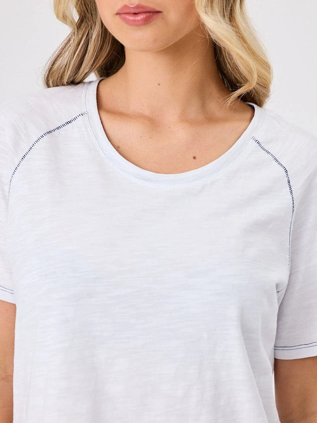 Woman wearing a white cotton t-shirt by Navy & Co, standing front-facing in natural light