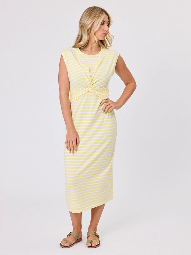 Woman wearing a coastal living inspired yellow striped cotton dress by Navy & Co, standing front-facing in natural light