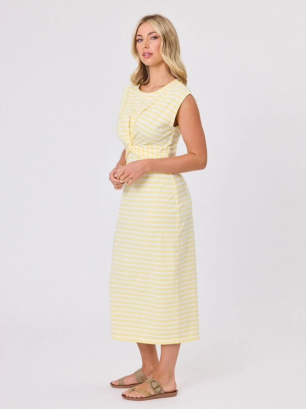 Woman wearing a coastal living inspired yellow striped cotton dress by Navy & Co, standing front-facing in natural light