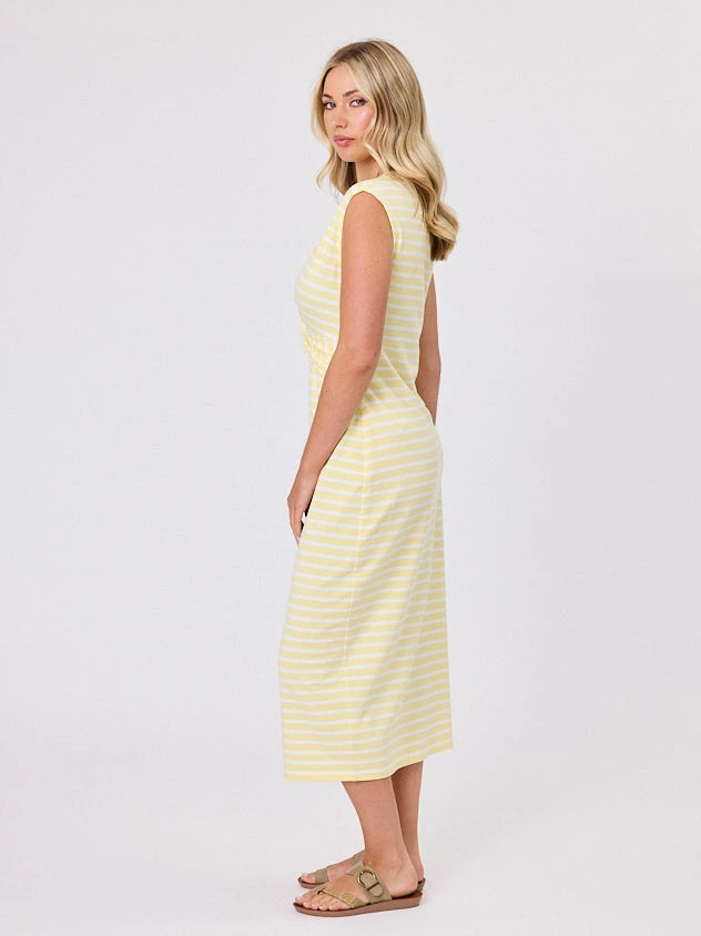Woman wearing a coastal living inspired yellow striped cotton dress by Navy & Co, standing front-facing in natural light