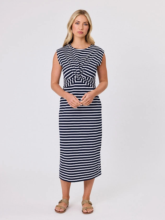 Woman wearing a coastal living inspired navy blue striped cotton dress by Navy & Co, standing front-facing in natural light