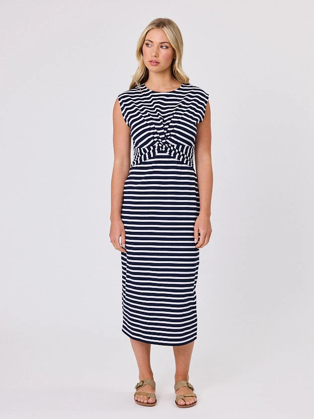 Woman wearing a coastal living inspired navy blue striped cotton dress by Navy & Co, standing front-facing in natural light