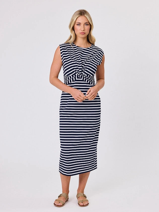 Woman wearing a coastal living inspired navy blue striped cotton dress by Navy & Co, standing front-facing in natural light