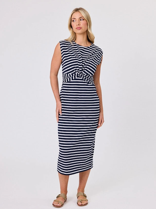 Woman wearing a coastal living inspired navy blue striped cotton dress by Navy & Co, standing front-facing in natural light
