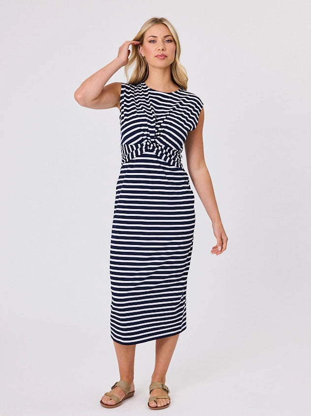 Woman wearing a coastal living inspired navy blue striped cotton dress by Navy & Co, standing front-facing in natural light
