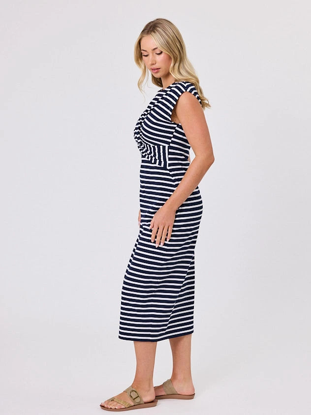 Woman wearing a coastal living inspired navy blue striped cotton dress by Navy & Co, standing front-facing in natural light