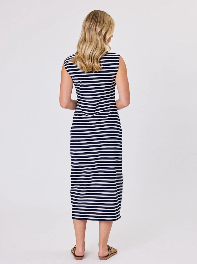 Woman wearing a coastal living inspired navy blue striped cotton dress by Navy & Co, standing front-facing in natural light