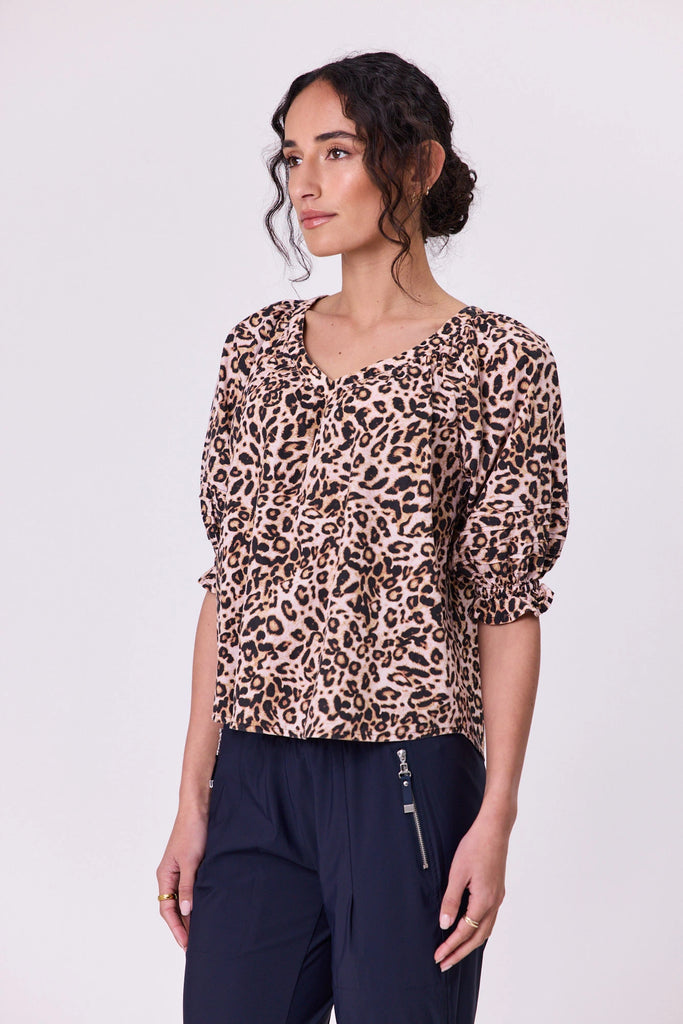 Woman wearing a vibrant aniaml print pattern cotton top by Navy & Co fashion brand, standing front-facing in natural light