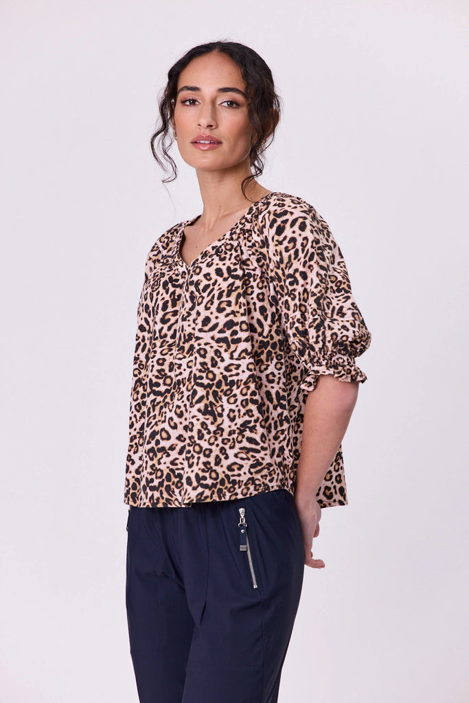 Woman wearing a vibrant aniaml print pattern cotton top by Navy & Co fashion brand, standing front-facing in natural light