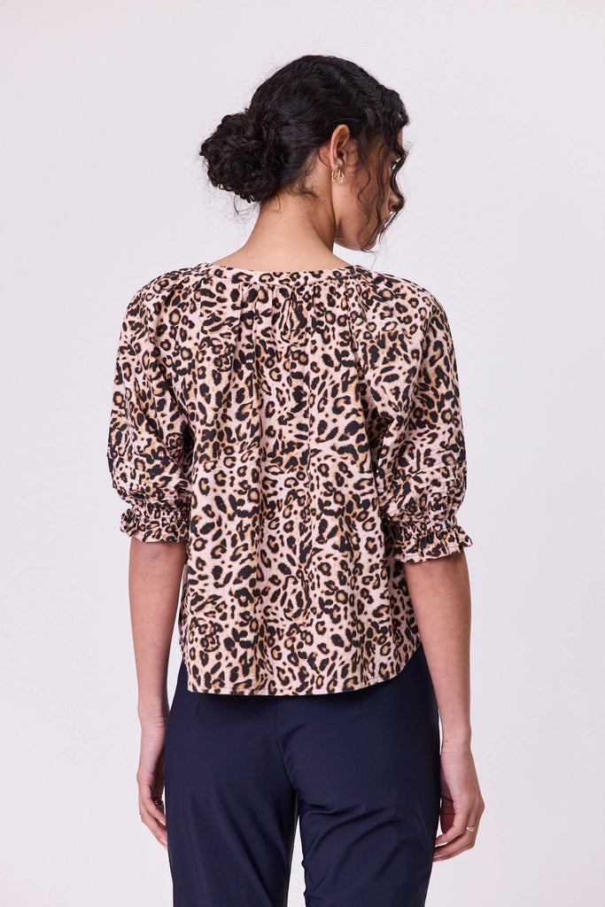 Woman wearing a vibrant aniaml print pattern cotton top by Navy & Co fashion brand, standing front-facing in natural light