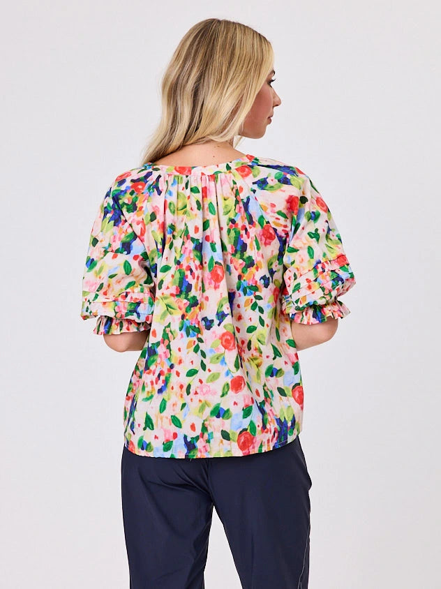 Woman wearing a vibrant colourful red floral pattern cotton top by Navy & Co fashion brand, standing front-facing in natural light