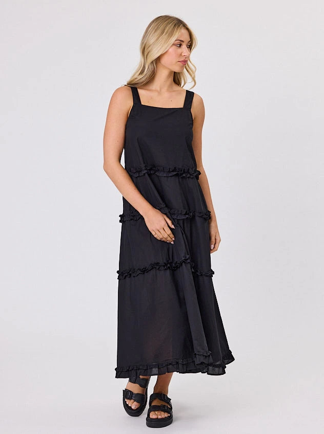 Woman standing front-facing in natural light wearing a black A-line Regalia dress by Navy & Co fashion brand 