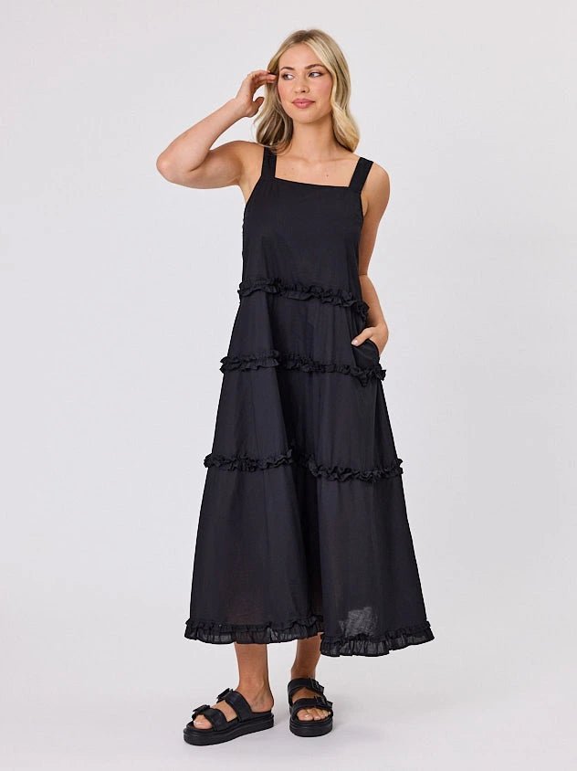 Woman standing front-facing in natural light wearing a black A-line Regalia dress by Navy & Co fashion brand 