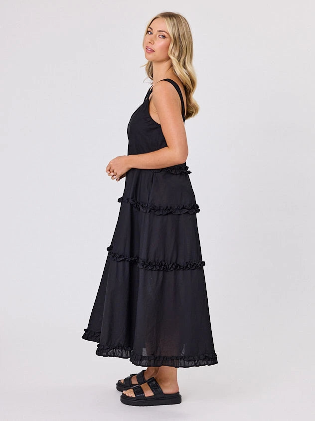 Woman standing front-facing in natural light wearing a black A-line Regalia dress by Navy & Co fashion brand 