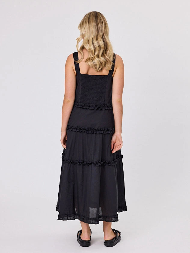 Woman standing front-facing in natural light wearing a black A-line Regalia dress by Navy & Co fashion brand 