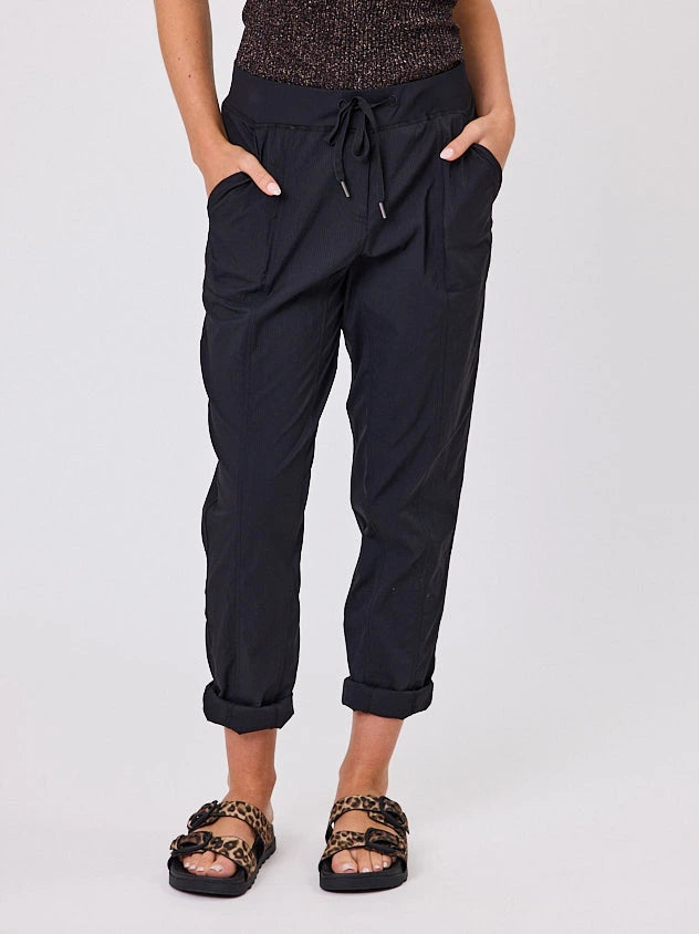 Woman standing front-on in studio light wearing black voyage crew pants, with white stich by Navy & Co nz fashion brand 