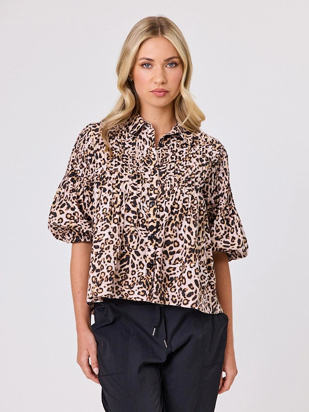 One woman dressed in cotton animal print bubble shirt, by Navy & Co a NZ fashion brand, she is standing front-on in studio light