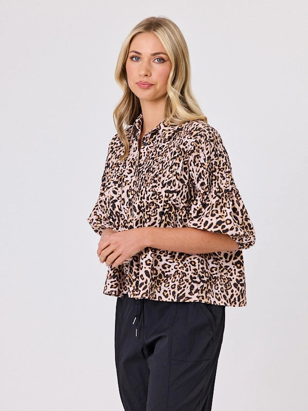 One woman dressed in cotton animal print bubble shirt, by Navy & Co a NZ fashion brand, she is standing front-on in studio light