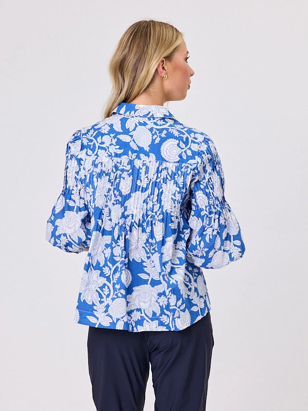 One woman dressed in blue tapestry cotton shirt, with bubble sleeves by Navy & Co a NZ fashion brand, she is standing front-on in studio light