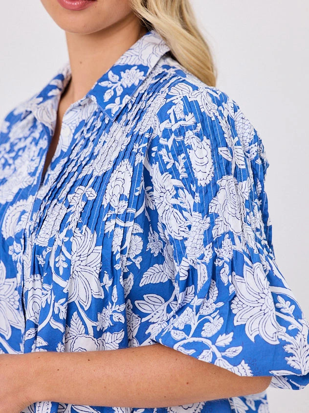 One woman dressed in blue tapestry cotton shirt, with bubble sleeves by Navy & Co a NZ fashion brand, she is standing front-on in studio light